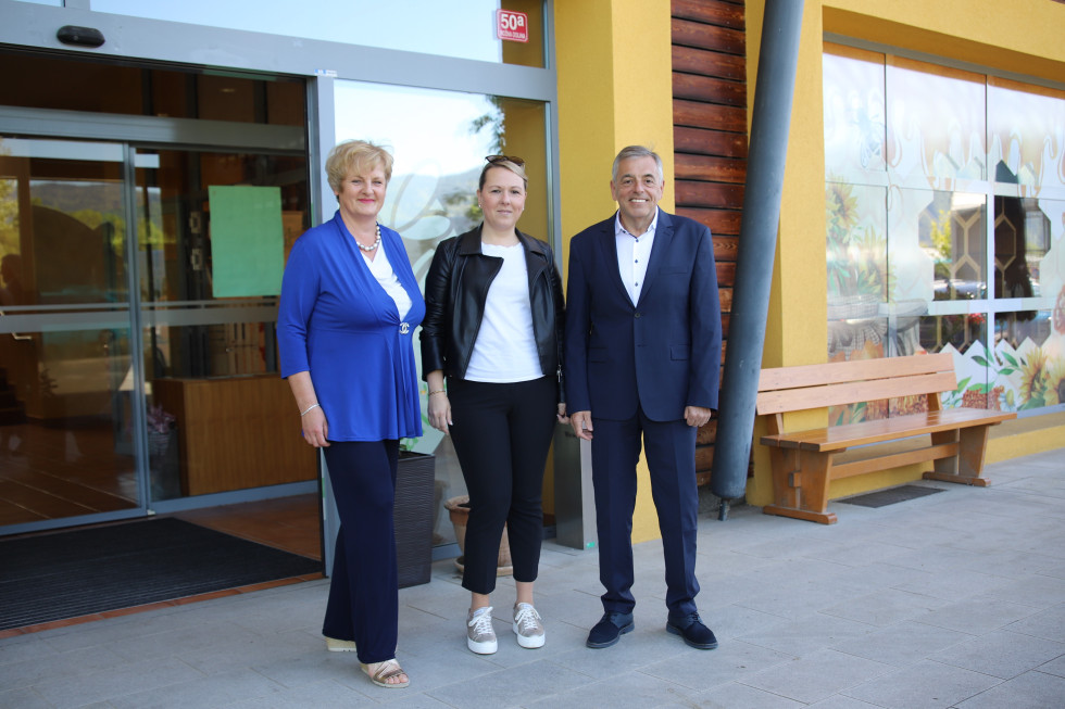 Tri osebe pred stavbo, na sredini ministrica Čalušić.