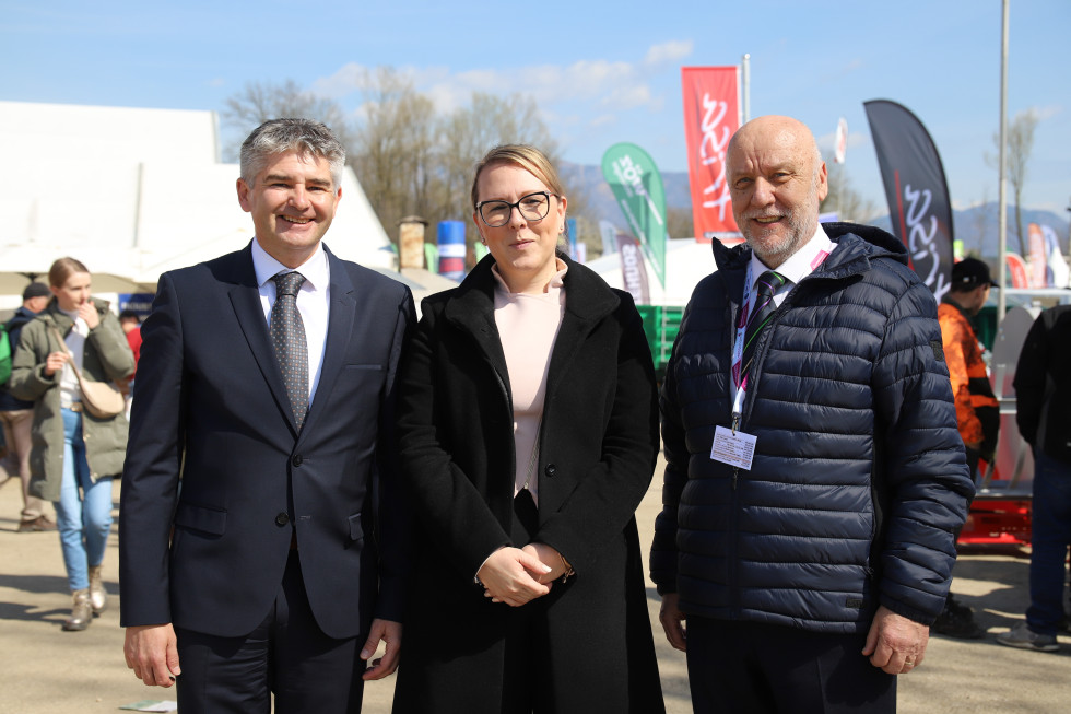 Tri osebe v vrsti, dva moška in na sredini ženska na prostem