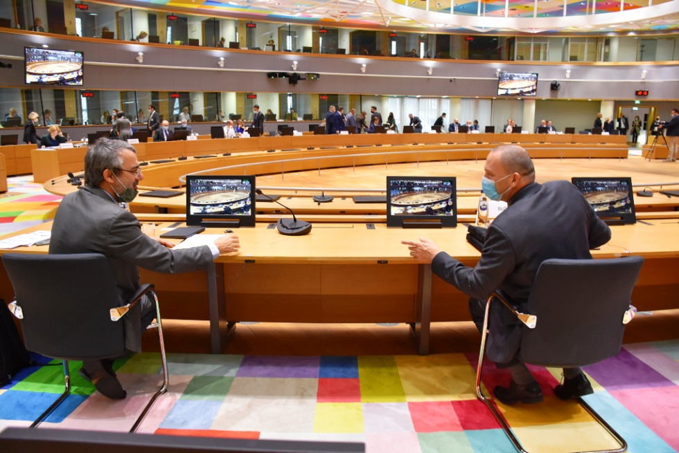 Dve osebi v oblekah se pogovarjata v dvorani Sveta evropske unije