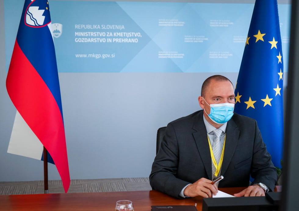 Minister Podgoršek sedi za mizo za njim zastava Slovenije