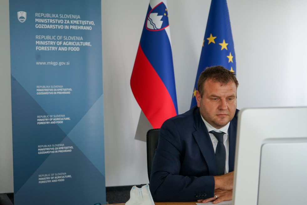 Secretary of State Aleš Irgolič in a dres sitting in front of a computer watching the meeting 