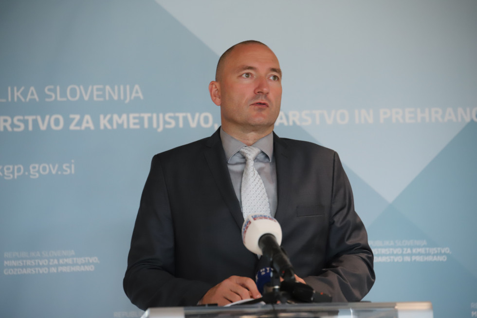 Minister v temni obleki za govorniškim pultom