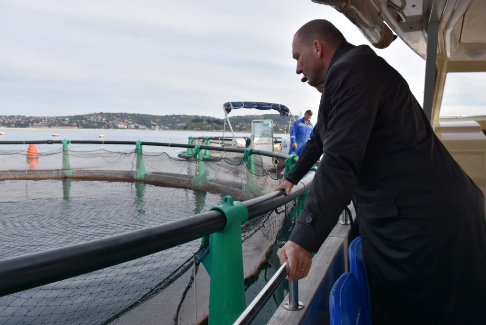 Minister si z ladje ogleduje ribogojnico.