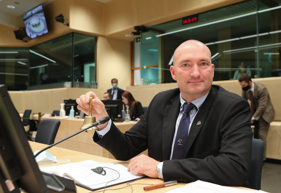 Minister is sitting in his chair with a bell in his hand.