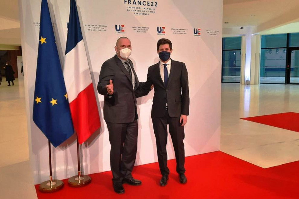 Slovenski in francoski minister stojita ob zastavah in se fotografirata. 