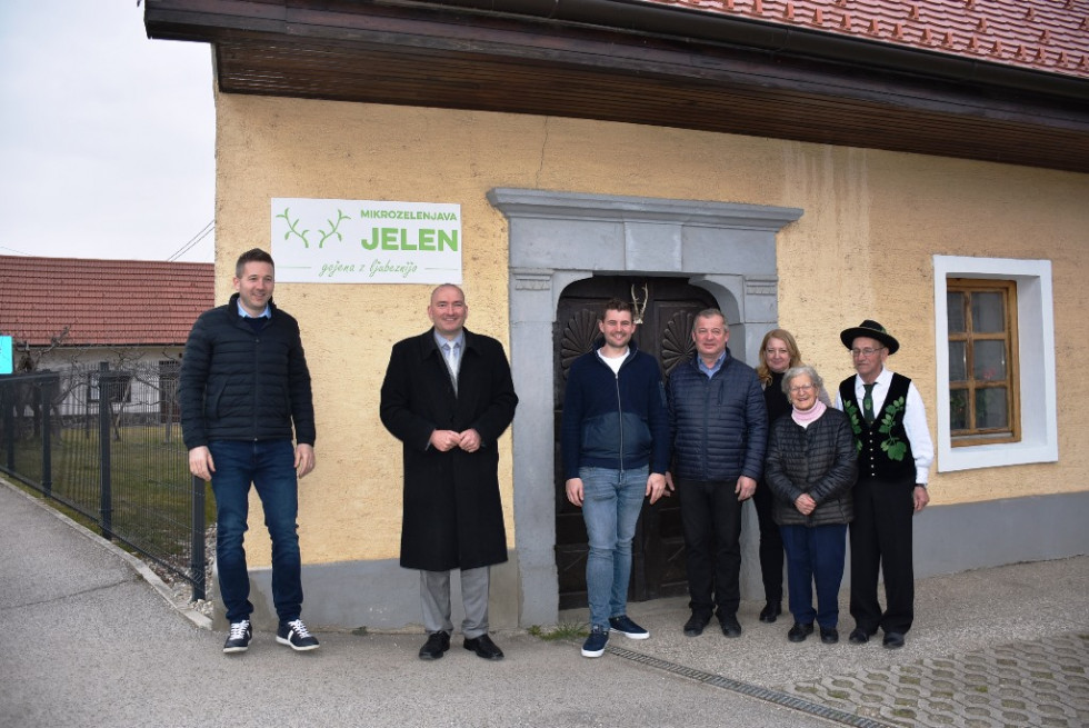 Več oseb stoji pred hišo in se fotografira.