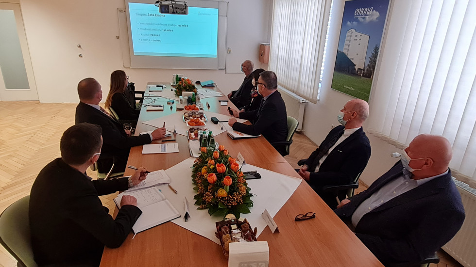Minister in predstavniki podjetja sedijo za mizo in se pogovarjajo.