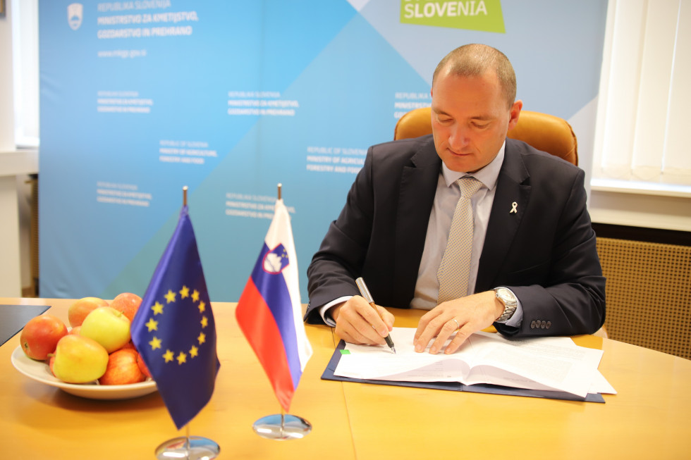 Minister podpisuje pravilnik. V rokah drži pero.