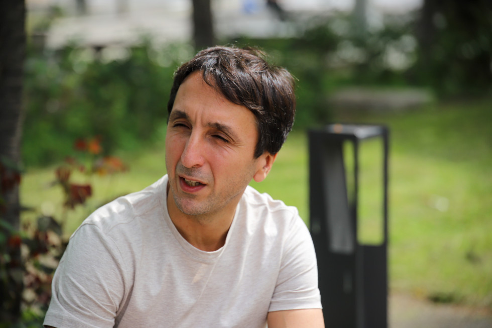 Profesor sitting on the bench and talking to the journalist. 