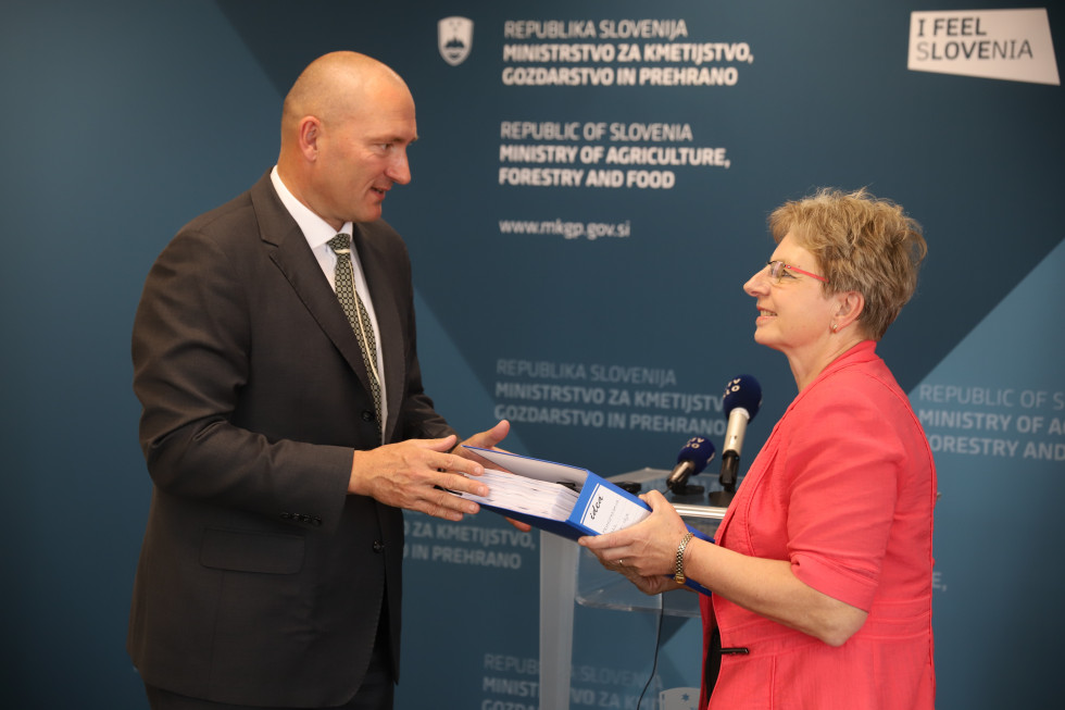 Dr. Jože Podgoršek hands the documents to Irena Šinko. 
