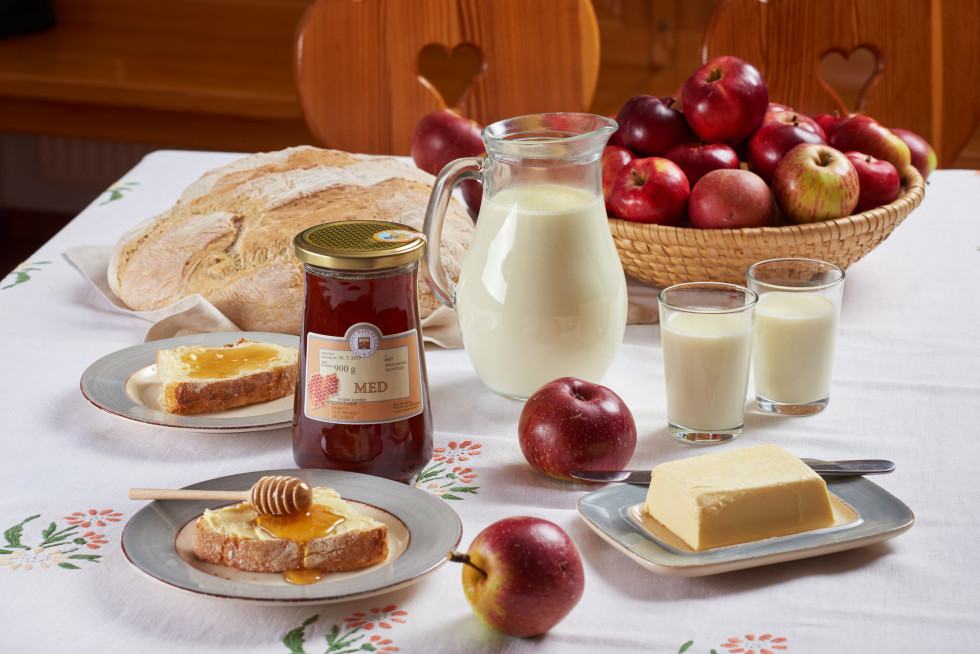 Pogled na mizo kjer so postavljeni kruh, maslo, jabolka in med 