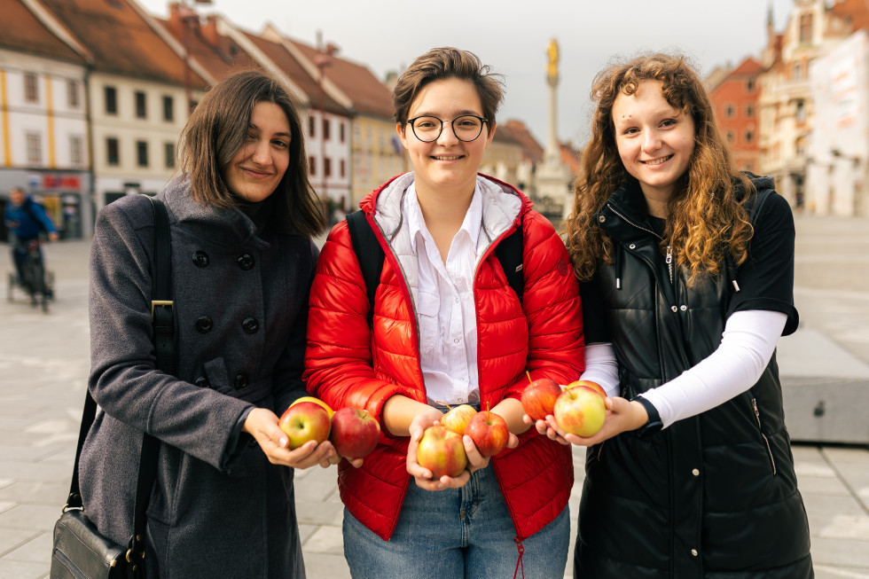 Tri dekleta imajo v rokah jabolka. 