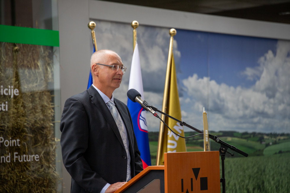 Državni sekretar stoji za govorniškim pultom in govori.