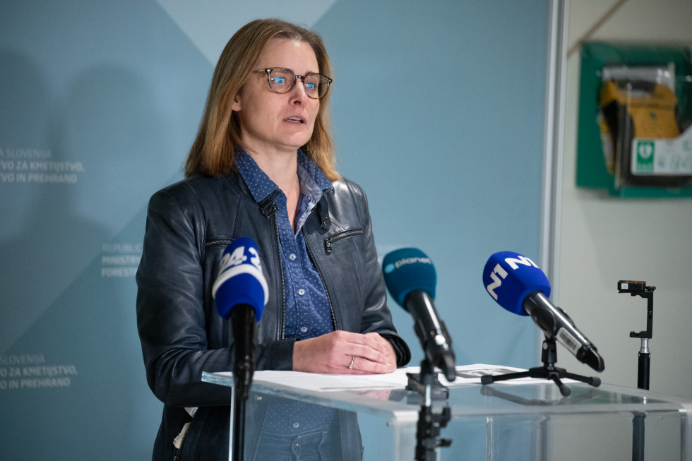 Predstavnica inšpekcije stoji za govorniškim pultom in govori.