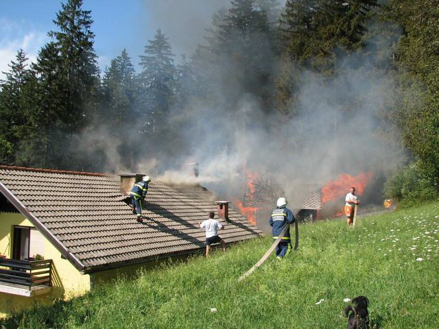 Požar na strehi hiše z gasilci, ki gasijo požar
