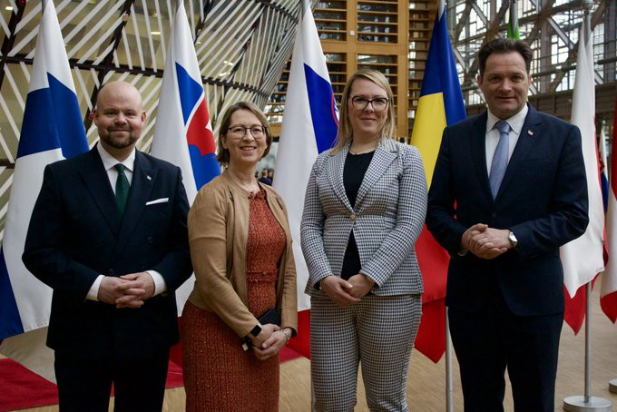 Ministers are taking a photo in front of the flags. 