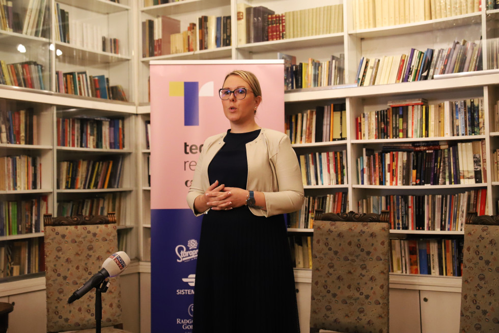Ministrica Mateja Čalušić stoji pred pingvinom z logotipom Tedna restavracij v sobi Pen kluba