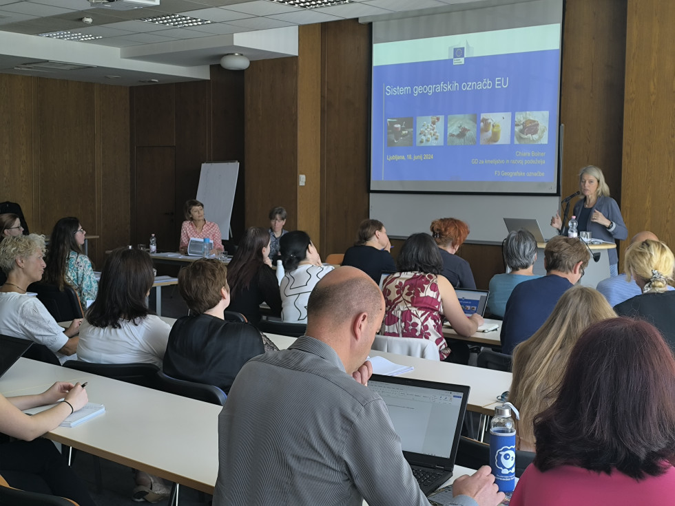 Konferenca o geografskih označbah in shemah kakovosti. Udeleženci sedijo v predavalnici in poslušajo predavateljico.