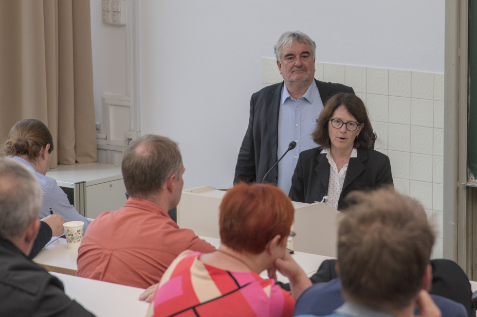 Generalna direktorica stoji za govorniško mizo in govori. 