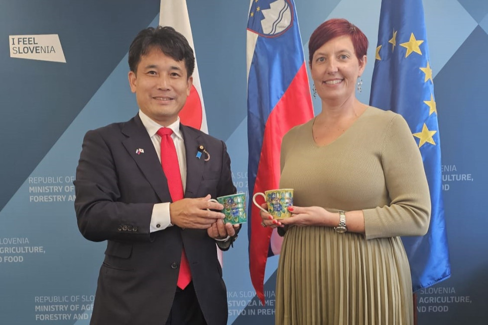 Državni minister in državna sekretarka stojita in se fotografirata.