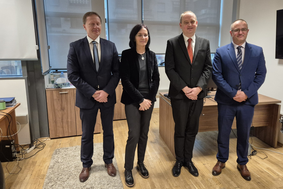 Več oseb stoji v dvorani in se fotografira. 