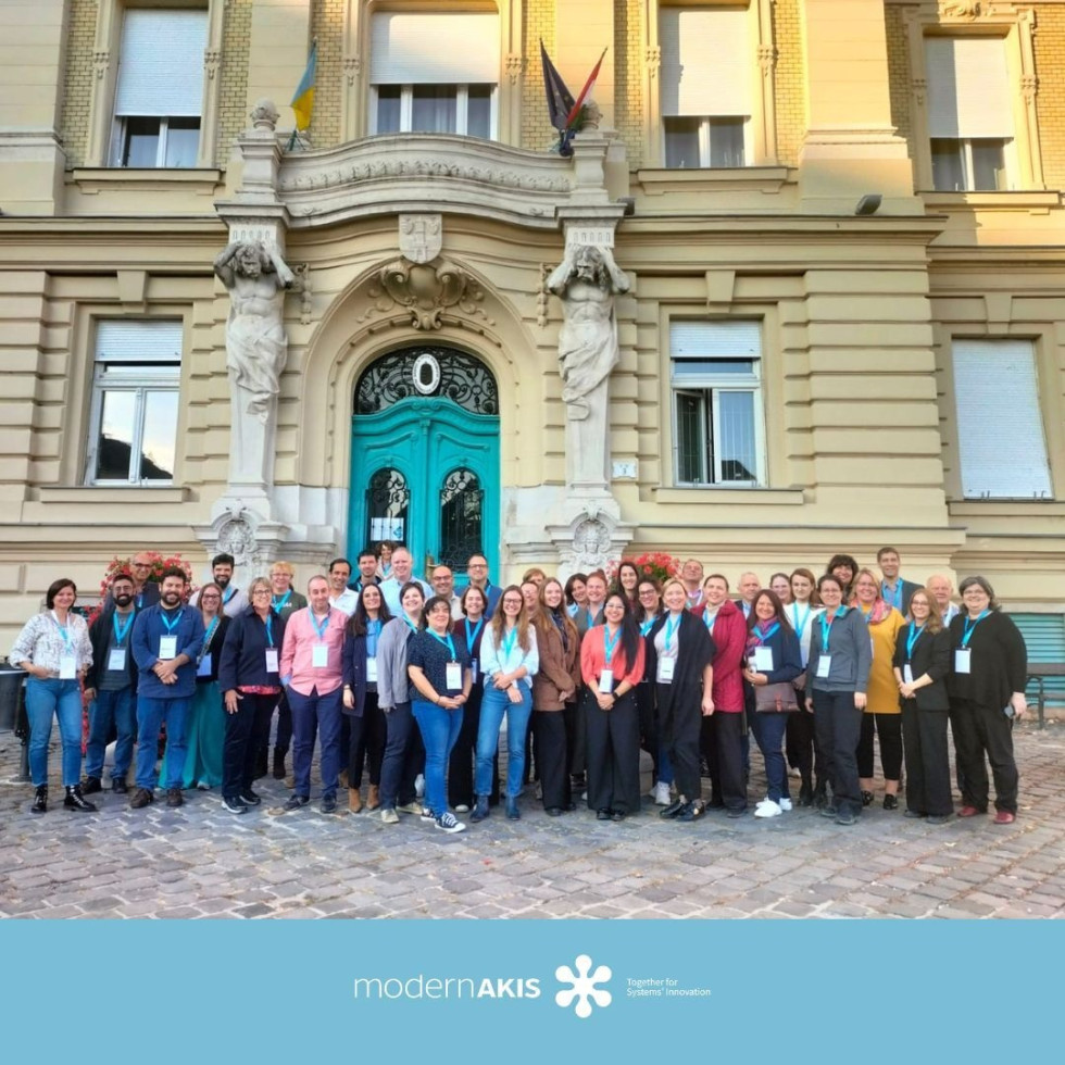 Več oseb stoji pred stavbo in se fotografira. 