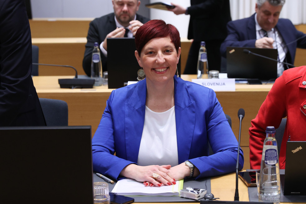 Oseba v modri obleki sedi za mizo. 