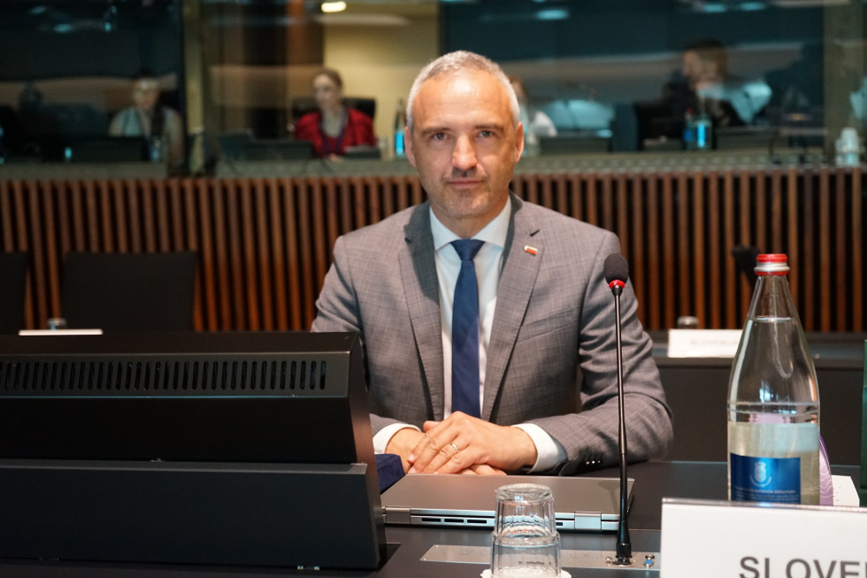 Minister sedi na svojem mestu in posluša zasedanje. 