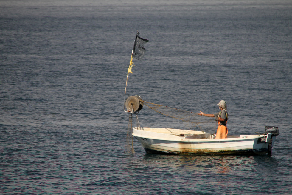 Ribič na čolnu lovi ribe