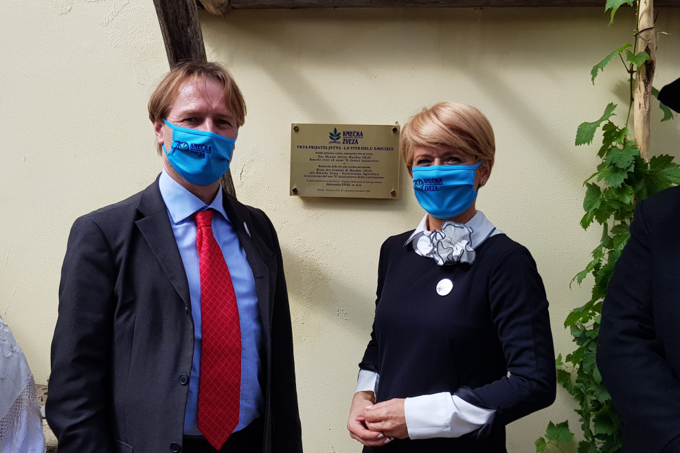 Ministreica z gospodom stoji pred prostori Kmečke zvetze Trst