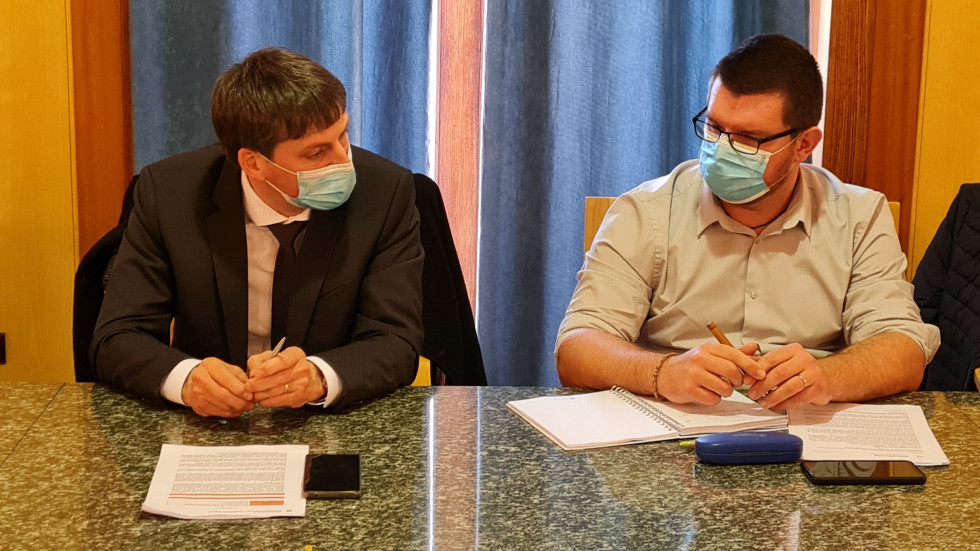Državni sekretar Anton Harej sedi za nizo in se pogovarja s sodelavci.