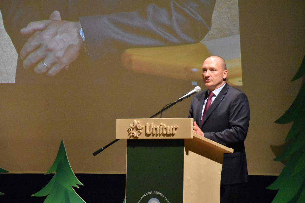 Minister stoji za govorniškim pultom. 