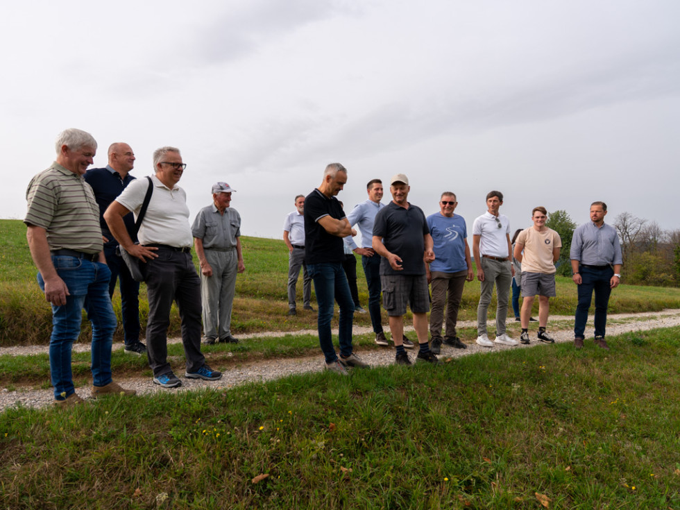 Več oseb stoji in si ogleduje škodo. 