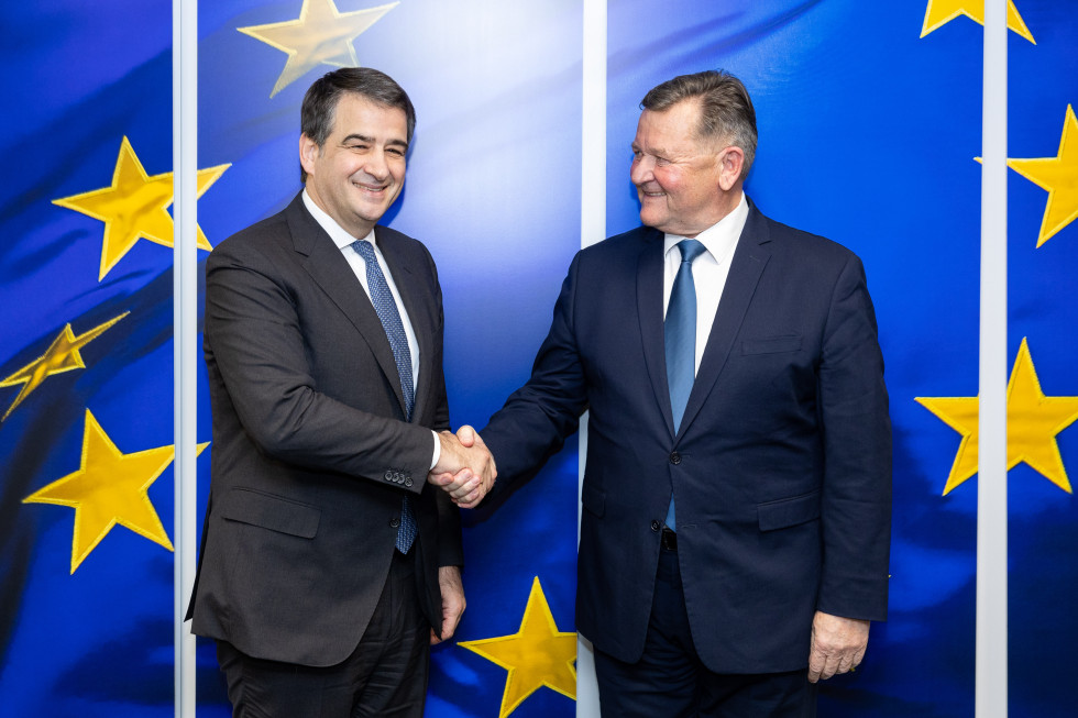 Commissioner Fitto and Minister Jevšek shaking hands in front of the EU flag