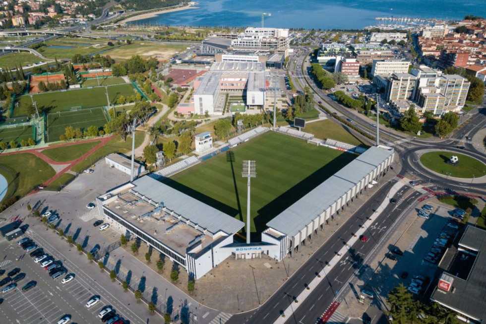 Aerial shot of the football stadium and its surroundings, with the sea in the background