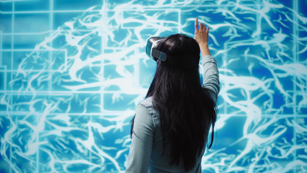 Ženska z očali za navidezno resničnost, ki opazuje hologram umetne inteligence.