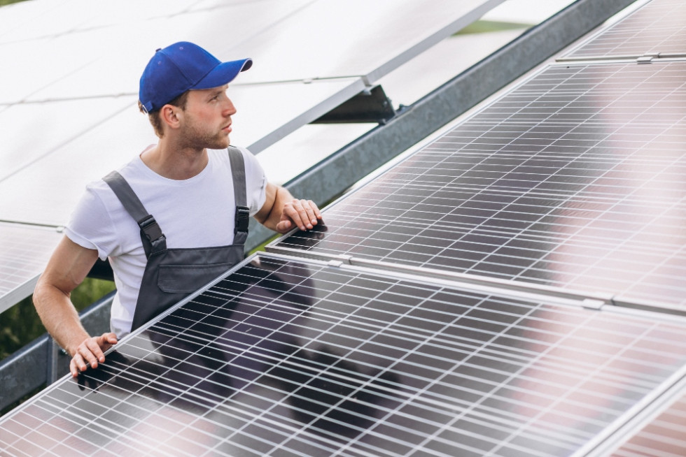 Moški na polju sončne elektrarne ob sončnih panelih