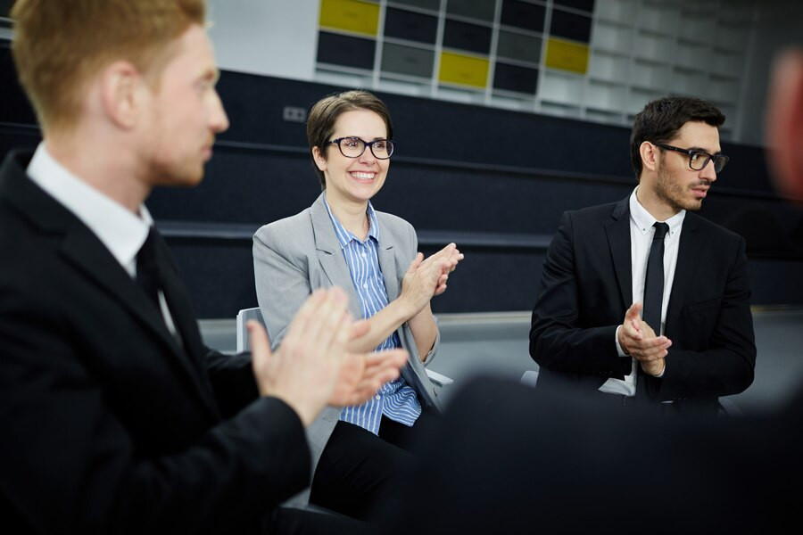 Symbolic photo of people from the world of business sitting in a circle on chairs and applauding