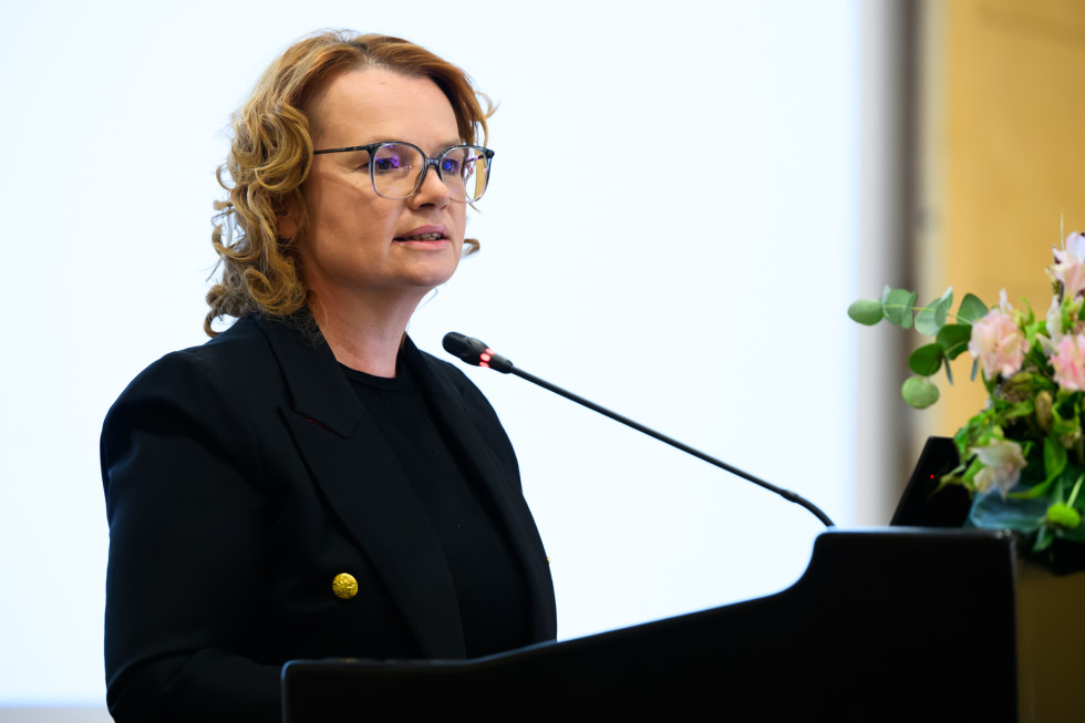 Ženska pred govorniškim odrom, na katerem je mikrofon.