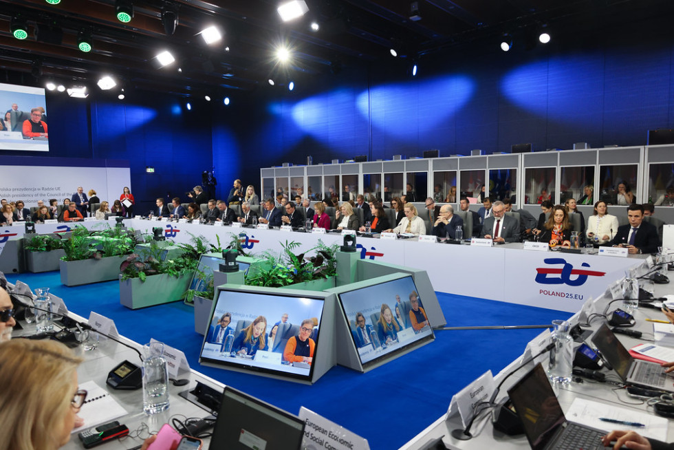 A large rectangular table with screens in the centre, with representatives from each Member State sitting at the table.