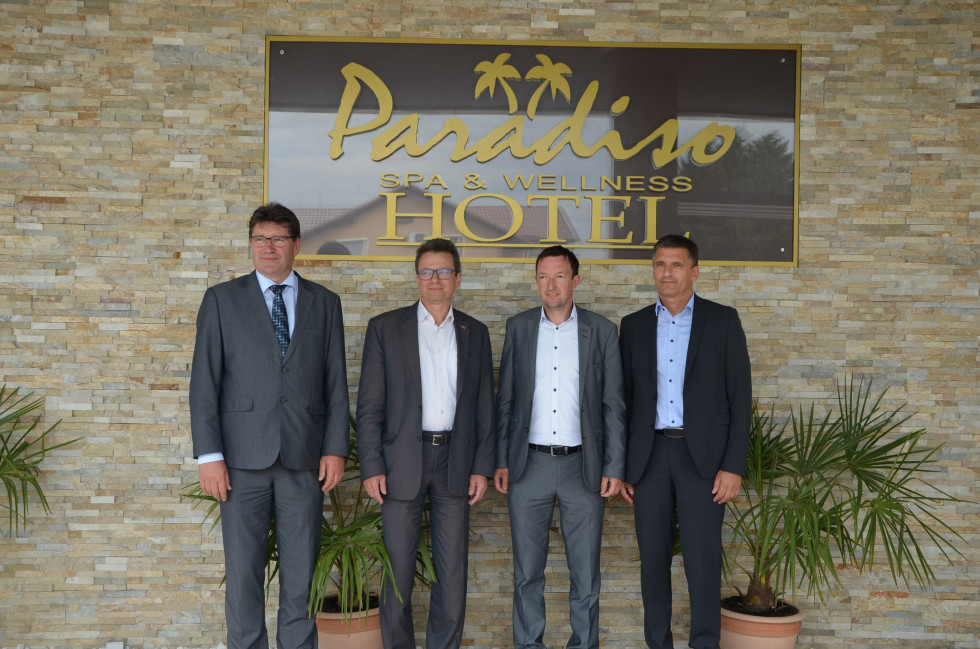 Štiri možje stojijo pred tablo na kateri piše hotel