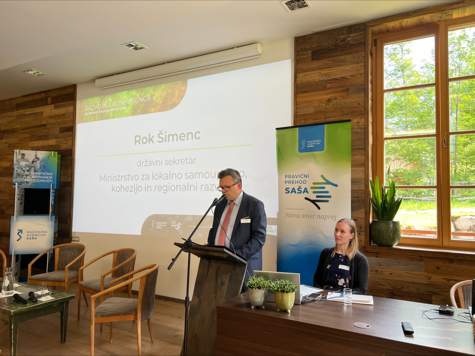 Državni sekretar Šimenc za govornico v dvorani. 