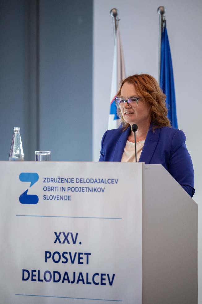 Ministrica za govorniškim pultom na dogodku.