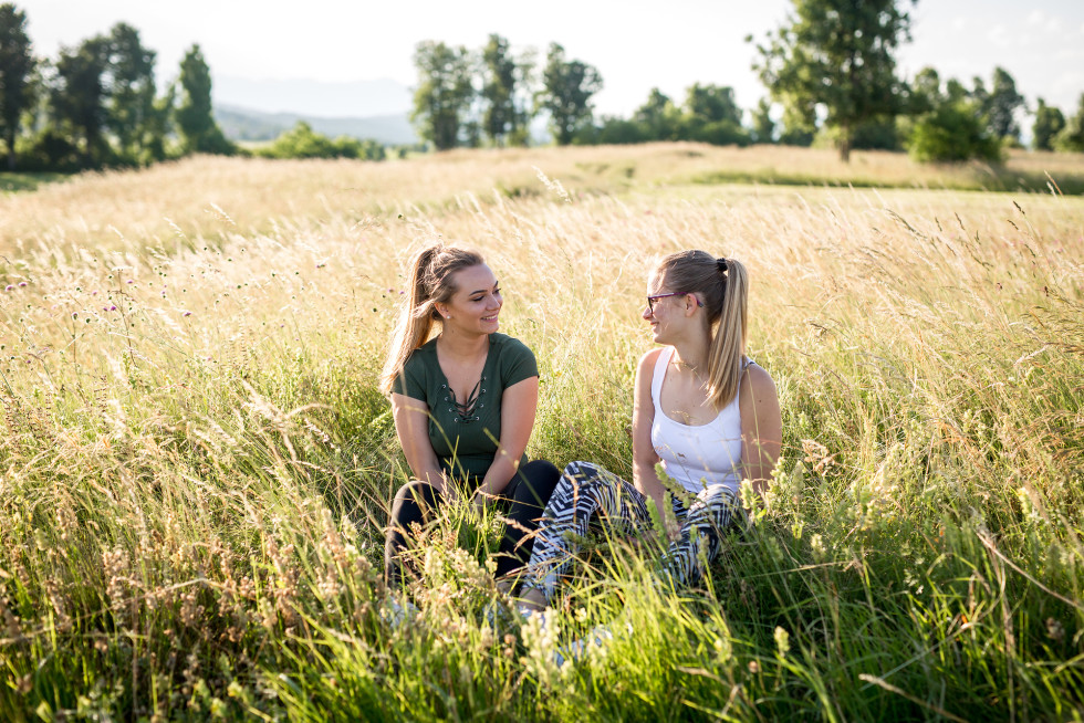 Two women are sitting in tall grass.