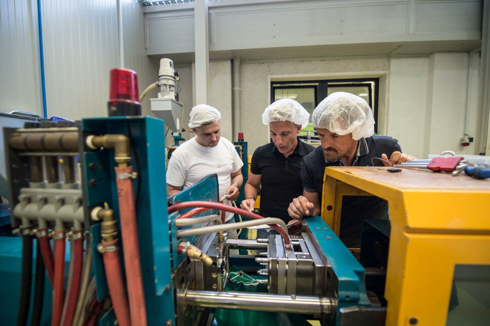 Three men standing by a machine in the production area. 
