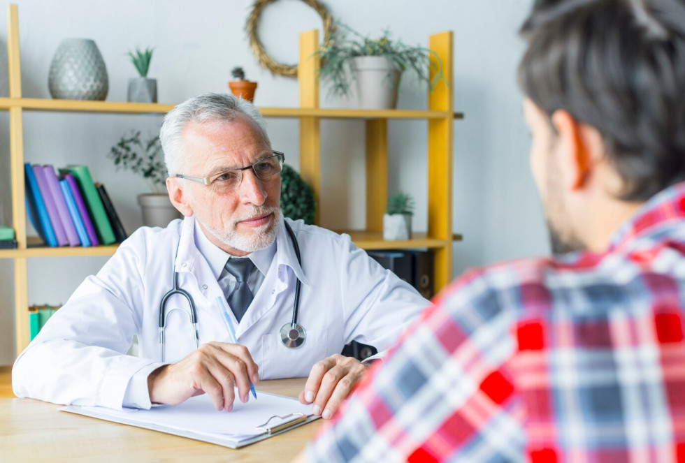 A bearded doctor listens to a patient. Symbolic photo.