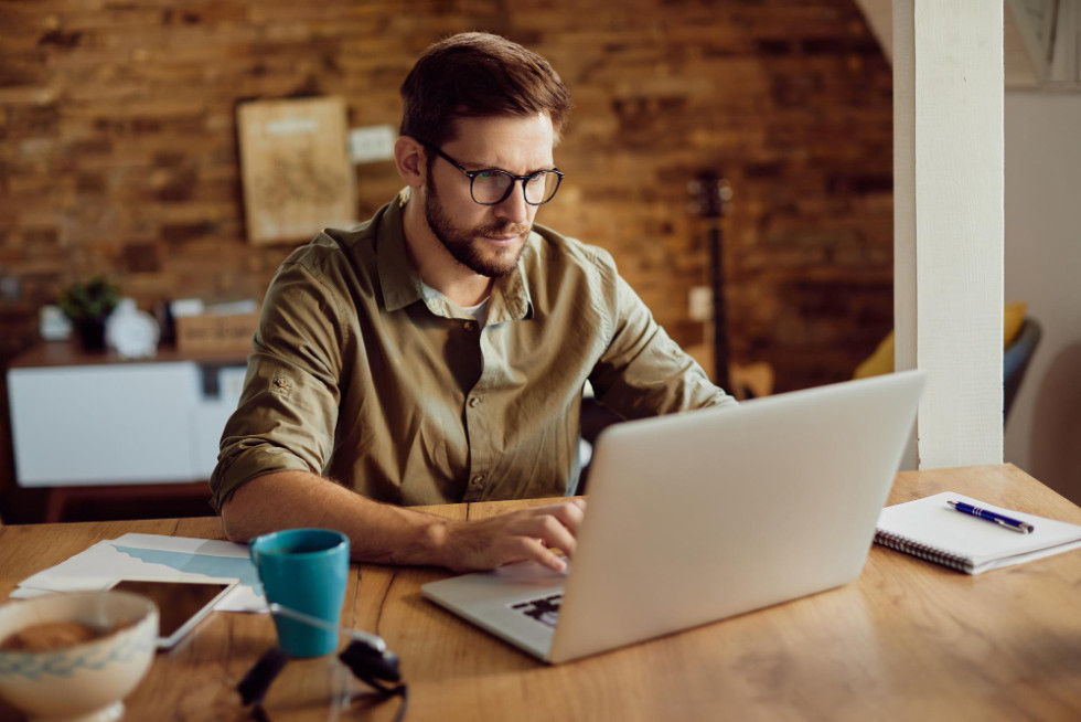 A man is sitting at a desk, working on his computer. 