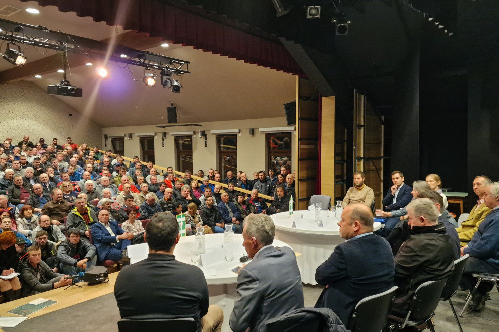 Poslušalci v dvorani spremljajo govorce na odru 