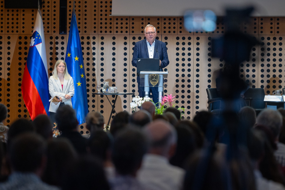 Minister Novak za govornico pred publiko v dvorani