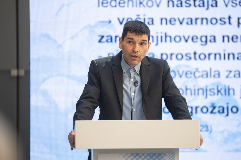dr. Matija Zorn, Geografski inštitut ZRC SAZU, predava za govornico, v ozadju se predvaja projekcija s podatki